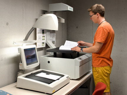 Studierender legt ein Buch auf einen Aufsichtscanner