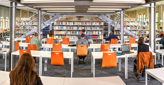 Studierende an Tischen im Lesesaal in Babelsberg vor Bücherregalen