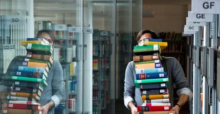 Student mit hohem Bücherstapel